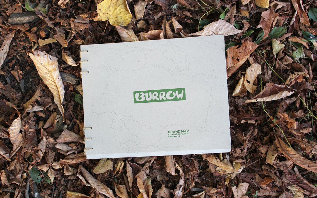 burrow brand standards booklet cover laying on a bed of fallen leaves