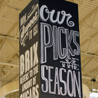 7 foot tall chalkboard pillar typographical illustrations advertising catering from prepared foods and seasonal produce in the produce department